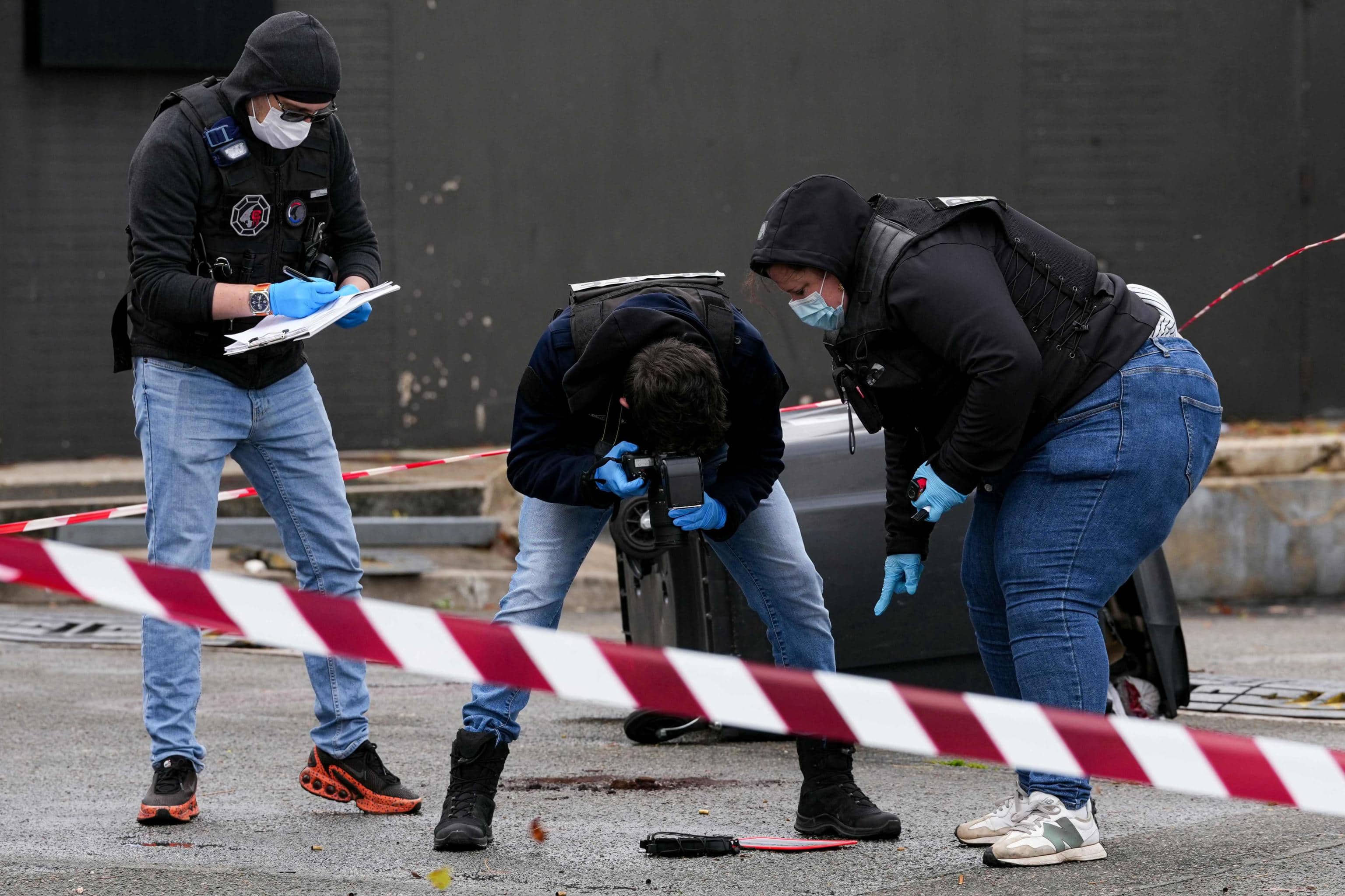 TOPSHOT - Police officers look at evidences on a site of a petrol station where a man opened fire from his car, killing one person and injuring four others according to police sources, in Trappes, Paris' suburb on October 23, 2026. 'This Friday morning, a man fired shots from his car at several people he came across in Trappes and La Verriere,' wrote Ali Rabeh, the mayor of Trappes, on Instagram. According to the Yvelines Prefecture, the emergency services are currently on the scene and the death toll 'has not yet been finalised'. (Photo by Dimitar DILKOFF / AFP)