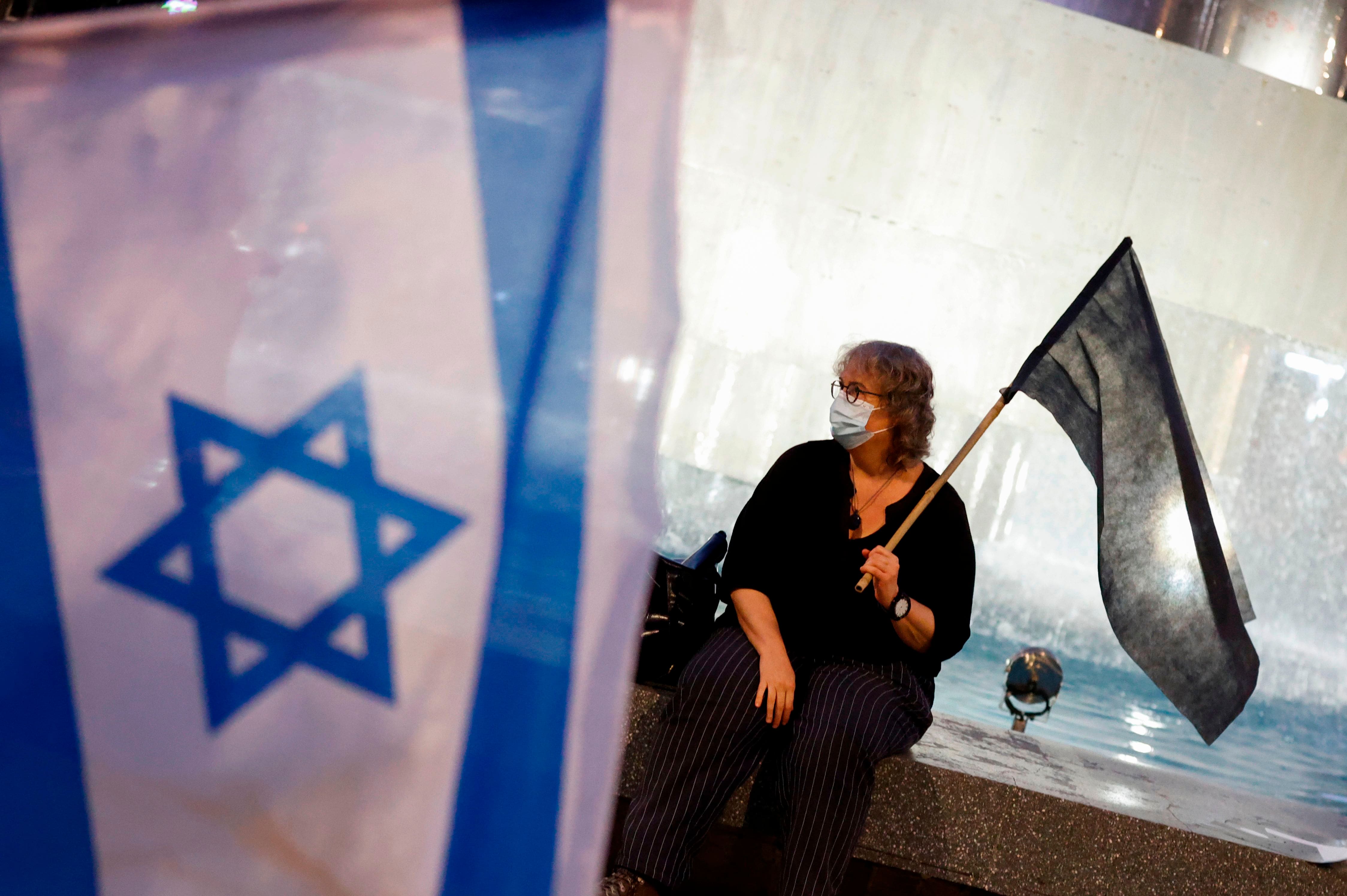 Israeli protesters, wearing protective masks due to the COVID-19 pandemic, take part in a demonstration against Prime Minister Benjamin Netanyahu and his handling of the coronavirus pandemic in the Israeli coastal city of Tel Aviv on October 8, 2020. (Photo by JACK GUEZ / AFP) (Photo by JACK GUEZ/AFP via Getty Images)