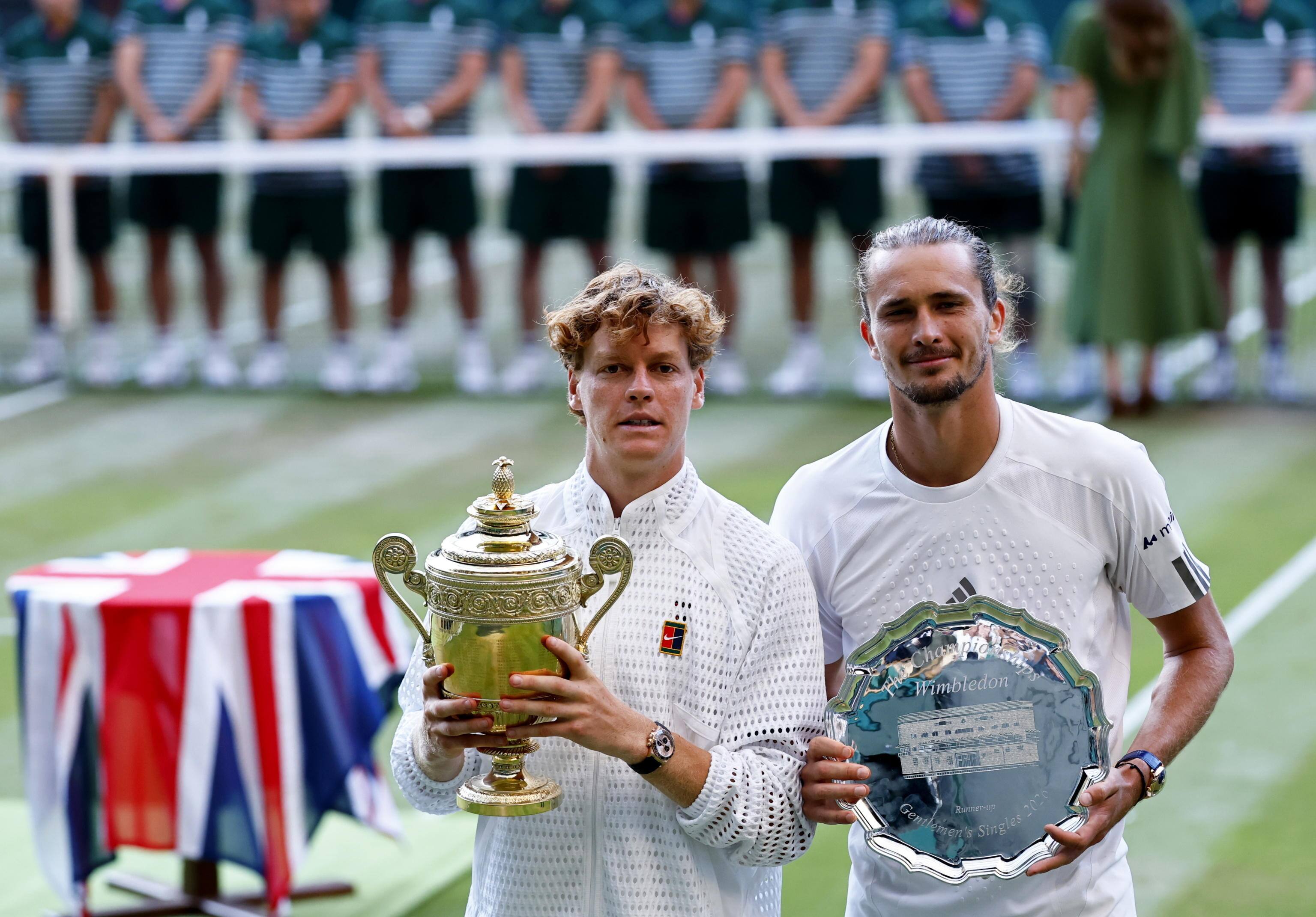 epa13107627 Jannik Sinner of Italy (L) celebrates with the trophy after winning the Men's Singles final against Alexander Zverev of Germany (R), with his runner-up trophy, at the Wimbledon Championships in London, Britain, 12 July 2026.  EPA/TOLGA AKMEN