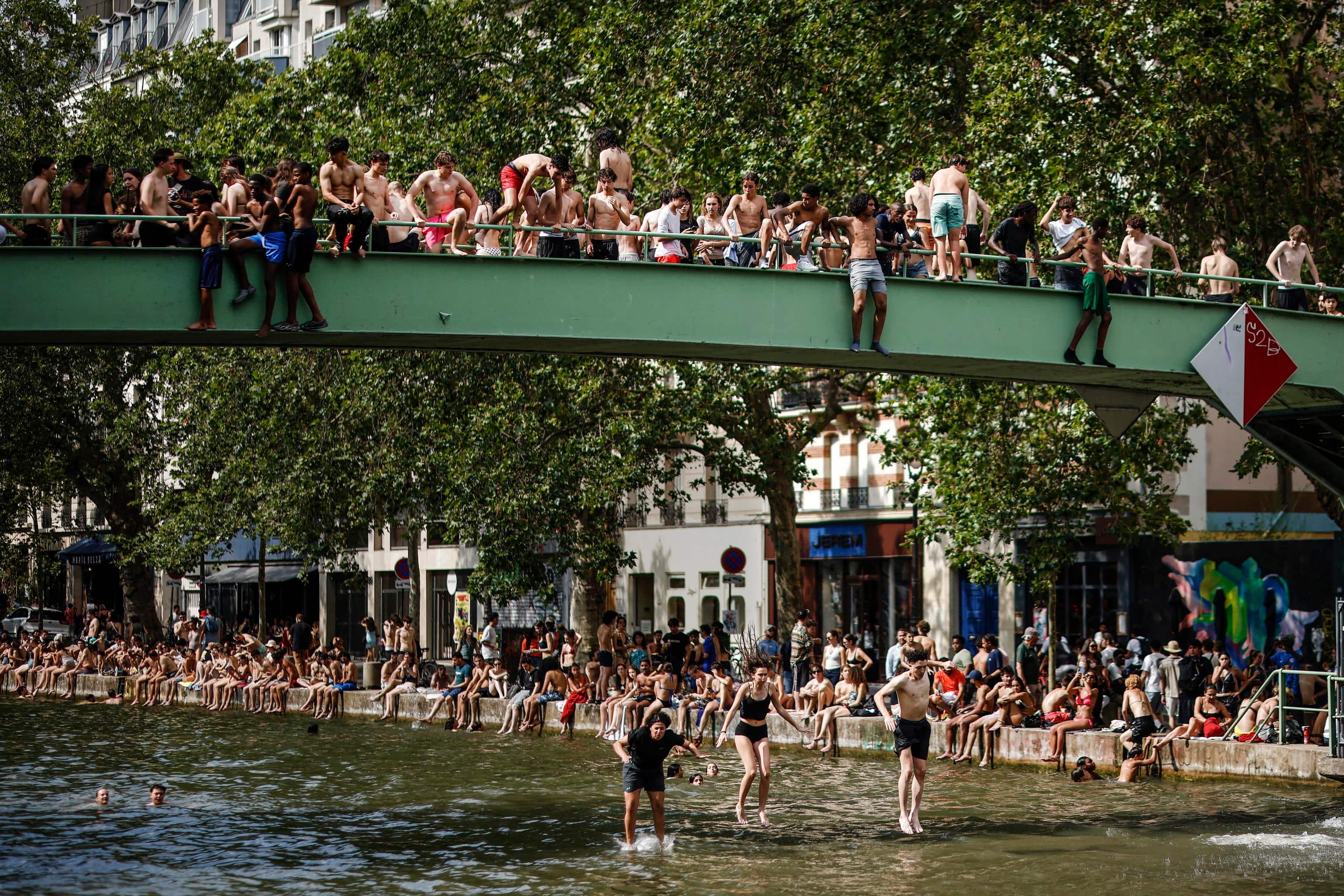 epa13052287 Youths jump from a bridge to cool off in the Canal Saint-Martin, in Paris, France, 20 June 2026. An intense heatwave is gripping Western and Central Europe, pushing temperatures far above seasonal norms for mid-June.  EPA/YOAN VALAT