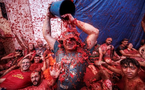epa13192504 People have fun after the battle with overripe tomatoes during the traditional 'Tomatina' fiesta in Bunol, Valencia, Spain, 26 August 2026. Thousands of people attend the annual event, where overripe tomatoes are thrown during the traditional tomato fight.  EPA/BIEL ALINO