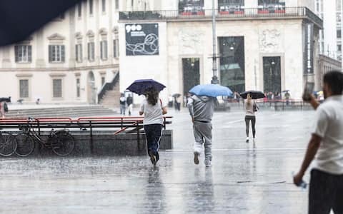 IPA88320891 - Milano, 09/09/2026, Piazza Duomo, Acquazzone intenso temporale si abbatte sulla città persone e turisti si riparano dalla pioggia e maltempo
