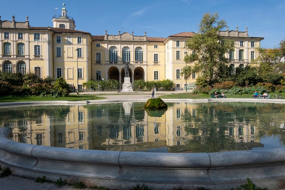 Milan, Italy - October 29, 2022: autumn day in the garden, baroque facade of Palazzo Dugnani, reflections in the fountain at historic public park Indro Montanelli. Lombardy