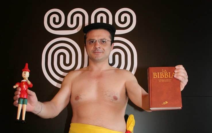 Cateno De Luca con in mano la bibbia e una miniatura di Pinocchio