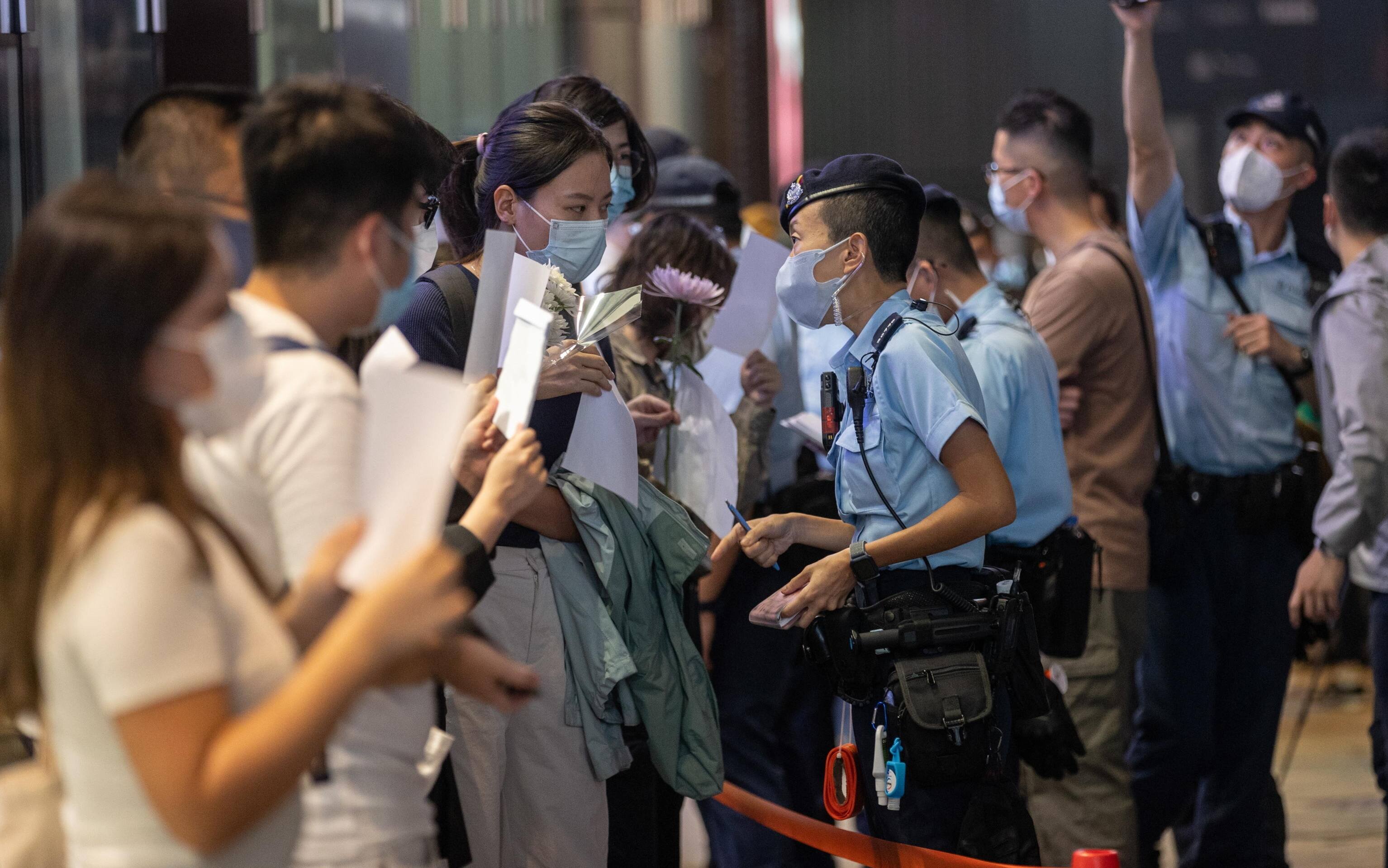 epa10334257 Police check mourners during a vigil for the victims of China s zero-COVID policy and the victims of the Urumqi fire in Hong Kong, China, 28 November 2022. Protests against China's strict COVID-19 restrictions have erupted in various cities including Beijing and Shanghai, triggered by a tower fire that killed 10 people in Xinjiang s capital, Urumqi.  EPA/JEROME FAVRE