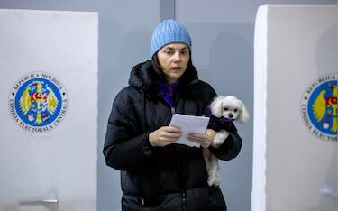 epa11670478 A woman holding her dog exits from voting cabin at poling stations in Chisinau, Moldova, 20 October 2024. Moldova holds presidential election and a referendum on whether to enshrine in the Constitution the country's path to EU membership on 20 October.  EPA/DUMITRU DORU