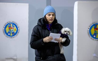 epa11670478 A woman holding her dog exits from voting cabin at poling stations in Chisinau, Moldova, 20 October 2024. Moldova holds presidential election and a referendum on whether to enshrine in the Constitution the country's path to EU membership on 20 October.  EPA/DUMITRU DORU