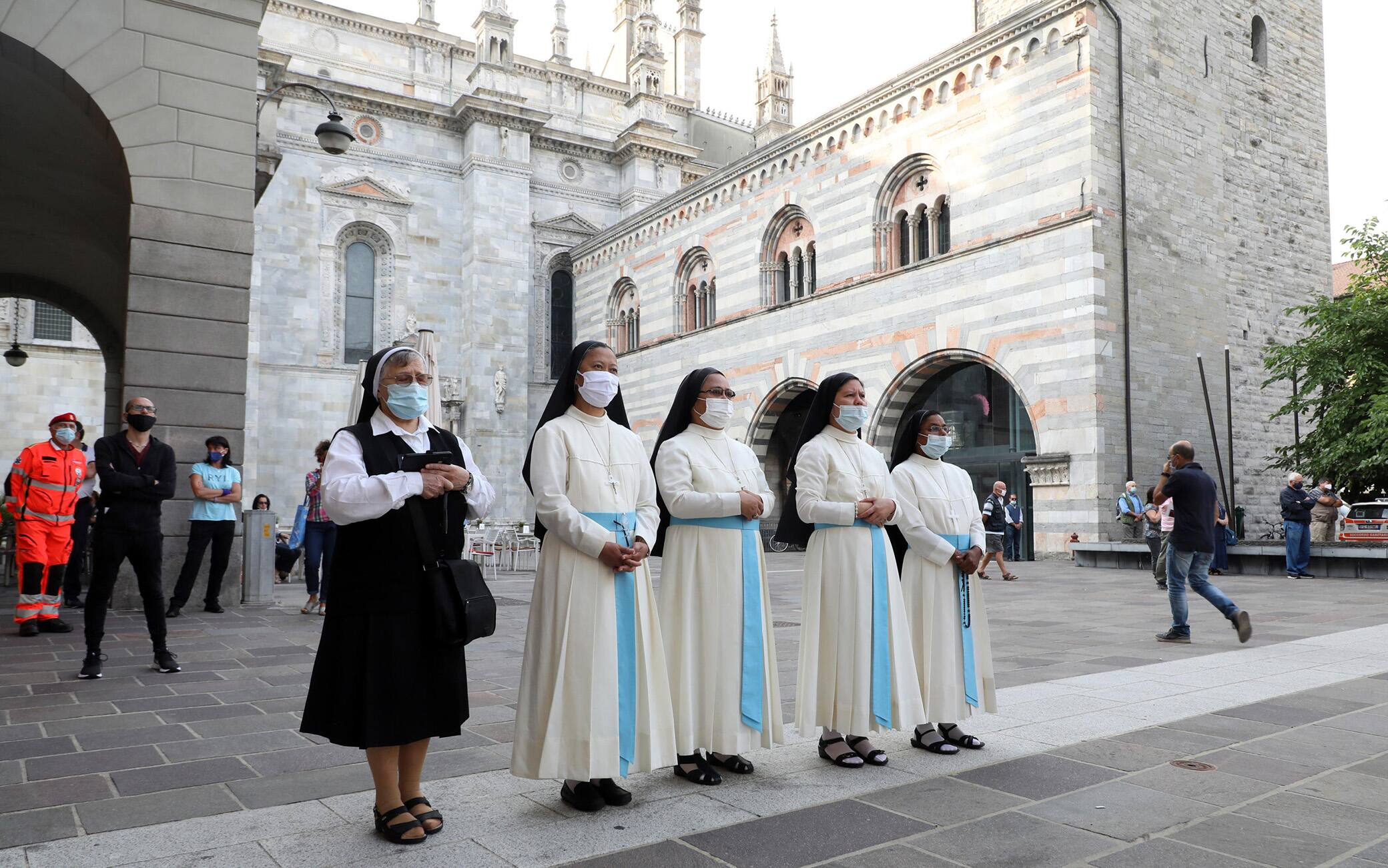 Alcune suore seguono su uno dei maxi schermi che sono stati allestiti nel centro di Como in occasione dell'orazione funebre per don Roberto Malgesini il parrocco assassinato da una delle persone di cui si prendeva cura. Como 19 Settembre 2020.ANSA / MATTEO BAZZI