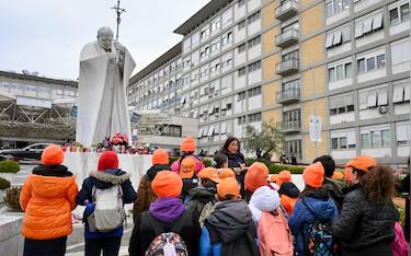 Alcuni giovani studenti durante un momento di preghiera sotto la statua di Giovanni Paolo II all ingresso del Policlinico Gemelli, dove è ricoverato Papa Francesco, Roma, 19 febbraio 2025.