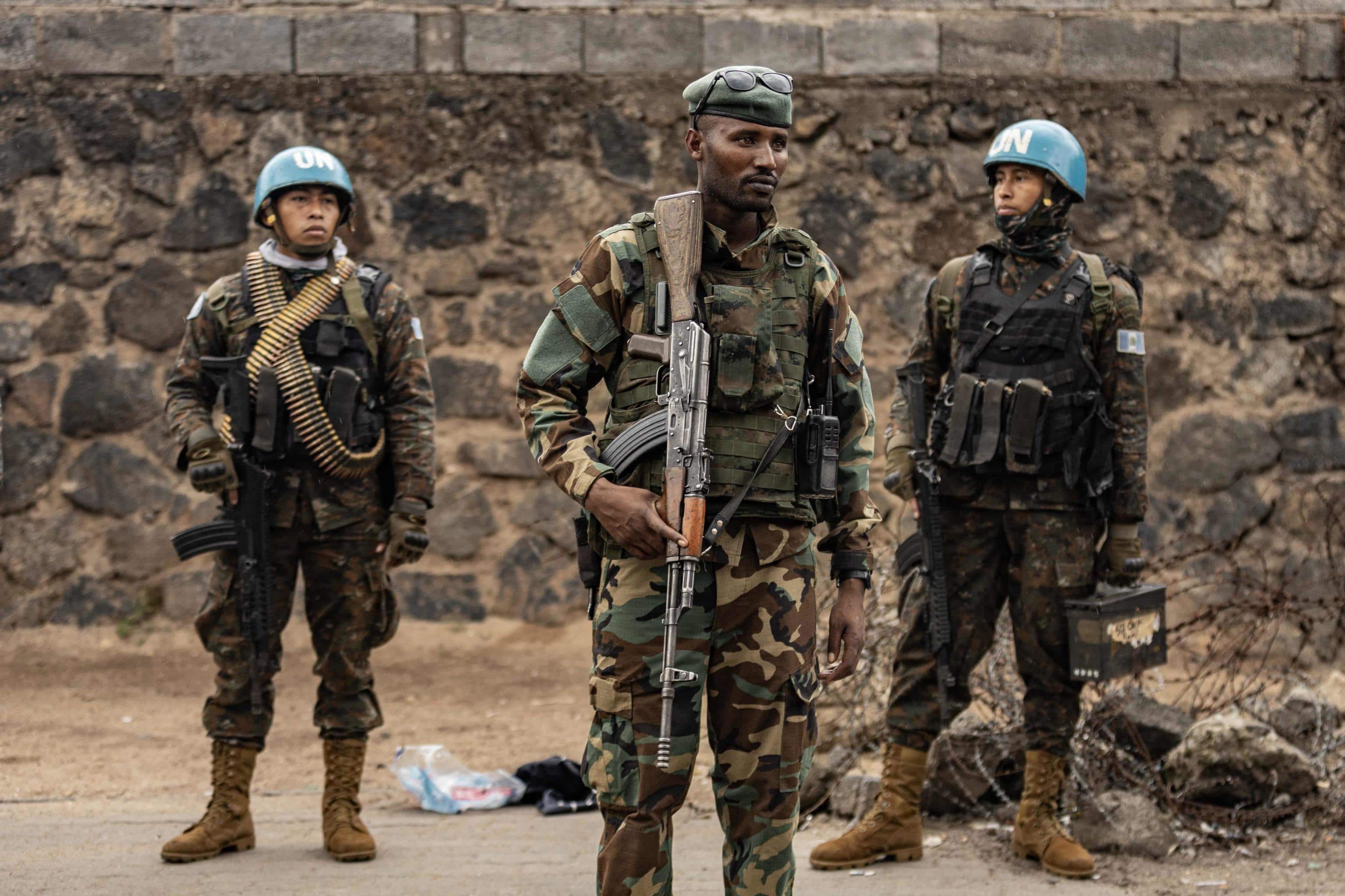 TOPSHOT - A members of the M23 armed group (C) stands in front of Guatemalan soldiers of the United Nations Organization Stabilization Mission in the Democratic Republic of the Congo (MONUSCO) as they monitor access to the border crossing into Rwanda, in Goma on January 29, 2025. Rwanda-backed fighters controlled almost all of the DR Congo city of Goma on January 29, 2025 where residents were re-emerging after days of deadly fighting and Angola urged leaders of both countries to urgently hold peace talks. After intense fighting that saw the M23 armed group and Rwandan troops seize the city's airport and key sites, calm returned to the mineral trading hub. (Photo by AFP)