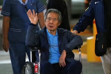 Peru's former President Alberto Fujimori waves to supporters as he is wheeled out of the Centenario Clinic in Lima on January 04, 2018, where he was hospitalised for the last twelve days and where he received a Christmas' eve pardon from President Kuczynski. Fujimori was pardoned days after his son Kenji abstained from voting on Kuczynski's impeachment, drawing other lawmakers with him to deny the opposition the votes necessary to remove the president from office over corruption allegations. (Photo by LUKA GONZALES / AFP) (Photo by LUKA GONZALES/AFP via Getty Images)