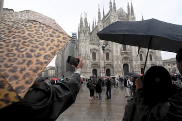 Milano Maltempo pioggia,  turisti in piazza Duomo
