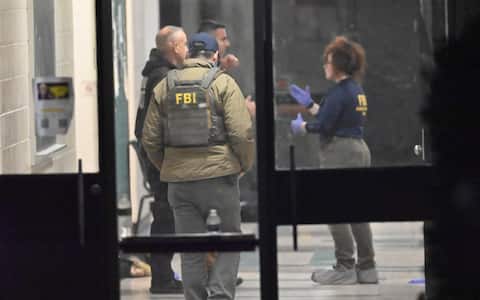 PROVIDENCE, RHODE ISLAND - DECEMBER 13: Members of the FBI Evidence Response Team work at the scene near a body, collect evidence and mark the area with evidence markers at Brown University in Providence, R.I., Saturday, Dec. 13, 2025, during a mass shooting that at least killed two people and wounded eight others. (Photo by Kyle Mazza/Anadolu via Getty Images)