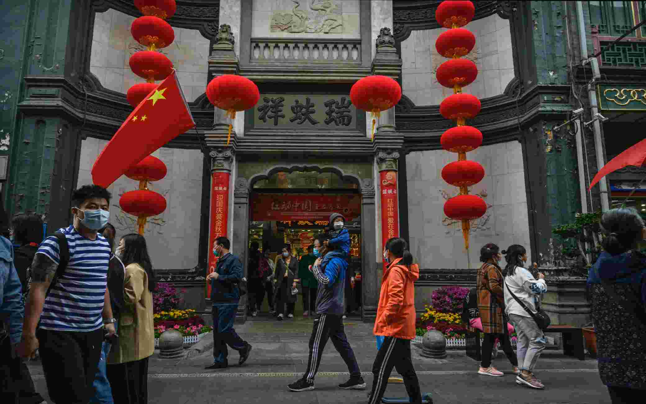BEIJING, CHINA - OCTOBER 08: Chinese tourists walk in a shopping area on October 8, 2020 during the final day of the 'Golden Week' holiday in Beijing, China. Officials are expecting the Golden Week holiday to boost Chinas consumer economy as people were encouraged to use the 8-day break to travel and spend. Tourist sites including the Great Wall were packed, with tickets selling out most days given epidemic restrictions and capacity capped at 75%. An estimated 550 million people are said to be on the move, with crowded train stations and attractions providing a sharply different view of a country that was largely shut down by the coronavirus outbreak earlier this year.  Officially, case numbers have remained low, though authorities are concerned about another wave of infection with flu season ahead. (Photo by Kevin Frayer/Getty Images)