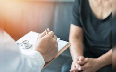 Geriatric doctor (geriatrician) consulting and diagnostic examining elderly senior adult patient (older person) on aging and mental health care in medical clinic office or hospital examination room