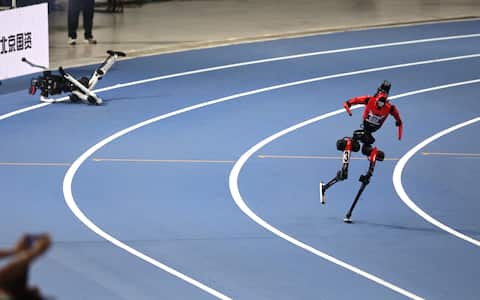 epa13184413 A humanoid robot runs pass another one that fell down during a 400m event at the 2026 World Humanoid Robot Games in the National Speed Skating Oval in Beijing, China, 22 August, 2026. The 2026 World Humanoid Robot Games are being held in Beijing until 26 August.  EPA/ANDRES MARTINEZ CASARES