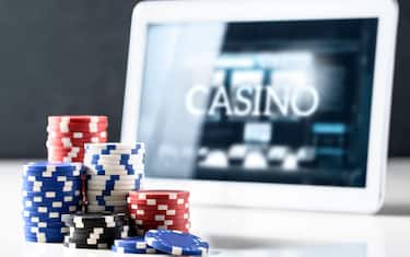 Online gambling on mobile casino concept. Stack of poker chips and tablet with slot machine on screen. Betting on internet and playing digital games for money with electronic device.