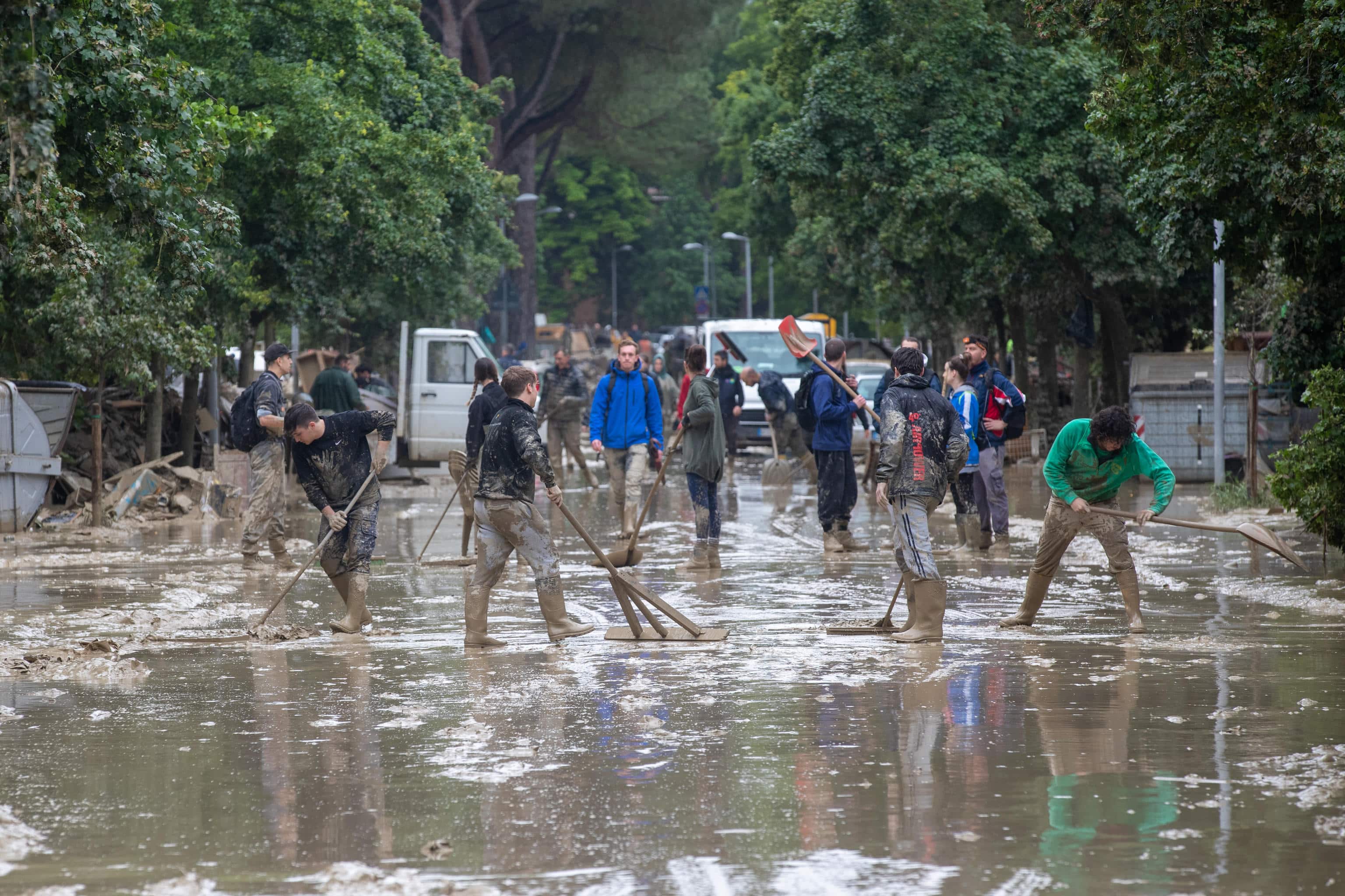 People walk as they clean a flooded street following the flood that is affecting Emilia Romagna, in Faenza, Italy, 19 May 2023. A new wave of torrential rain is hitting Italy, especially the northeastern region of Emilia-Romagna and other parts of the Adriatic coast. ANSA/ FABRIZIO ZANI -PASQUAlE BOVE