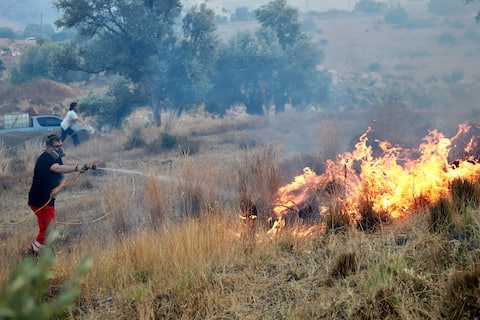 epa13140359 A volunteer works to extinguish a fire in low-lying vegetation in Krya Vrysi, Rethymno, Crete, Greece, 29 July 2026. More than 150 firefighters, supported by four helicopters and four firefighting aircraft, were deployed to tackle the blaze. Two firefighters died while battling the fire, according to the Greek Fire Service.  EPA/NIKOS CHALKIADAKIS