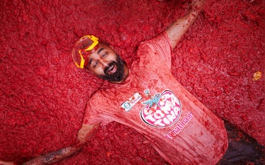 epa13192448 A man takes part in the battle with overripe tomatoes during the traditional 'Tomatina' fiesta in Bunol, Valencia, Spain, 26 August 2026. Thousands of people attend the annual event, where overripe tomatoes are thrown during the traditional tomato fight.  EPA/BIEL ALINO