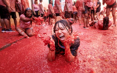 epa13192446 A woman takes part in the battle with overripe tomatoes during the traditional 'Tomatina' fiesta in Bunol, Valencia, Spain, 26 August 2026. Thousands of people attend the annual event, where overripe tomatoes are thrown during the traditional tomato fight.  EPA/BIEL ALINO