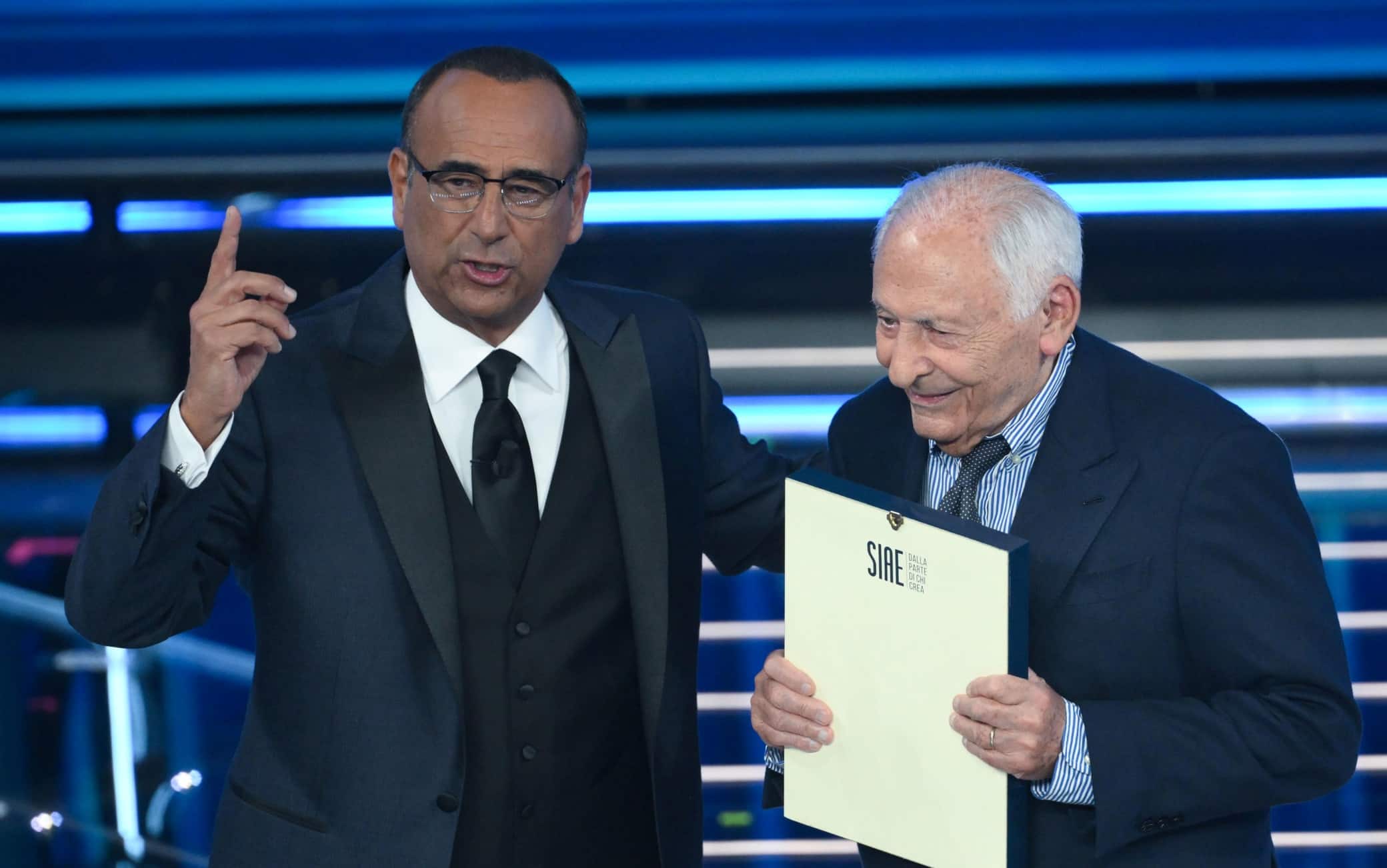 (L-R) Sanremo Festival host and artistic director Carlo Conti and Italian musician Mogol on stage at the Ariston theatre during the 76th edition of the Sanremo Italian Song Festival, in Sanremo, Italy, 26 February 2026. The Music Festival runs from 24 to 28 February 2026. ANSA/ETTORE FERRARI 