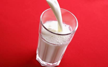 Milk being poured into a glass on red background