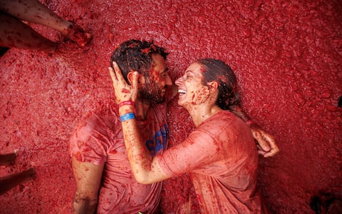 epa13192445 A couple takes part in the battle with overripe tomatoes during the traditional 'Tomatina' fiesta in Bunol, Valencia, Spain, 26 August 2026. Thousands of people attend the annual event, where overripe tomatoes are thrown during the traditional tomato fight.  EPA/BIEL ALINO