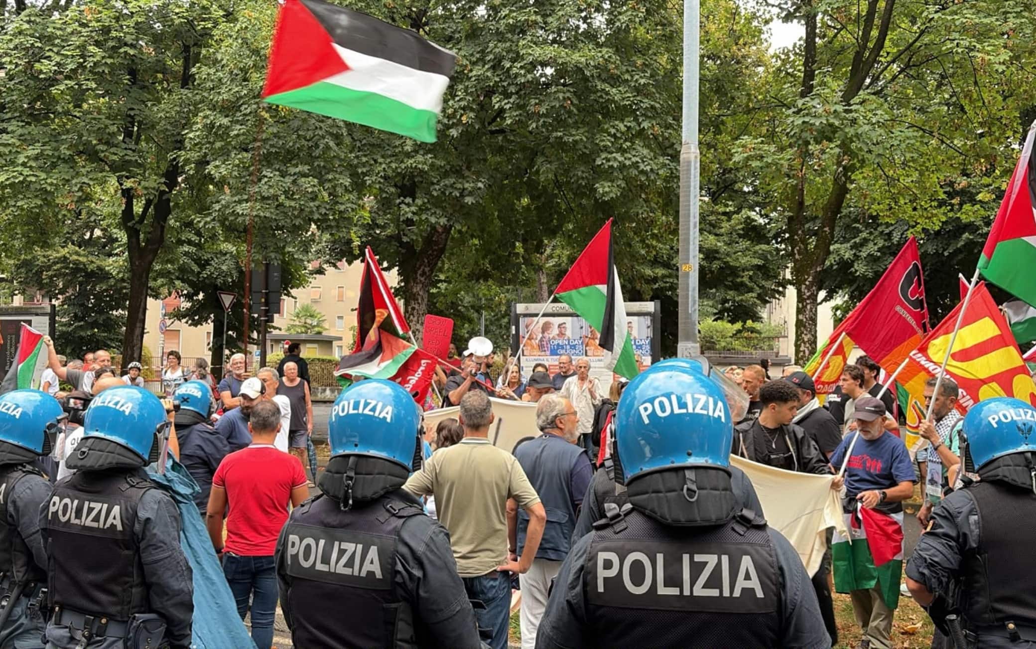 Persone sventolano bandiere palestinesi accanto ad agenti di Polizia in tenuta anti sommossa nelle vicinanze dello stadio New Balance Arena in concomitanza con i playoff della coppa europea tra Atalanta e 'Hapoel Tel Aviv, Bergamo, 20 luglio 2026. ANSA/MICHELE MARAVIGLIA
