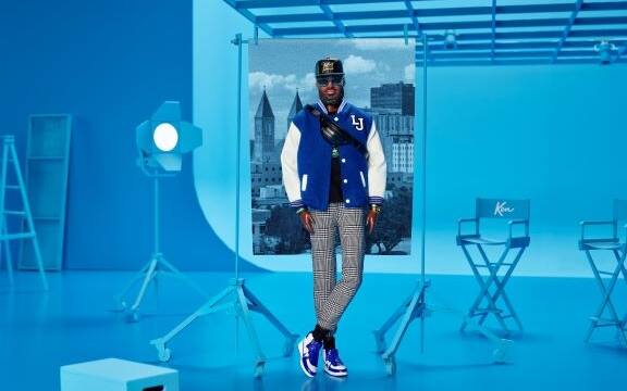 Immagine della bambola Ken di LeBron James su sfondo azzurro con una giacca casual blu con cucite le iniziali LJ