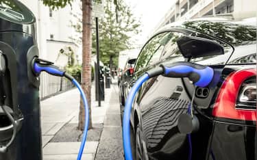 Electric car plugged in and changing on urban city street