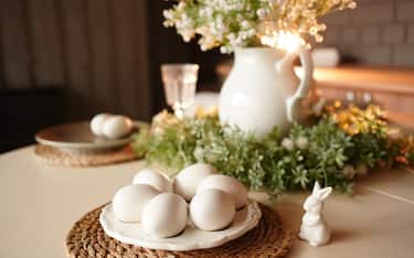 Table decorated with white eggs, a ceramic bunny, and a vase of flowers, creating a festive spring atmosphere