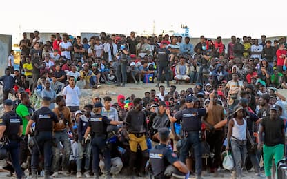 epa13150615 Police officers direct migrants at El Trampolin beach in Ceuta, Spain, 04 August 2026. According to Spanish officials, around 2,500 migrants remain in Ceuta following last week's massive border rush from Morocco, with many living in overcrowded reception centers or sleeping outdoors on beaches and in parks.  EPA/REDUAN