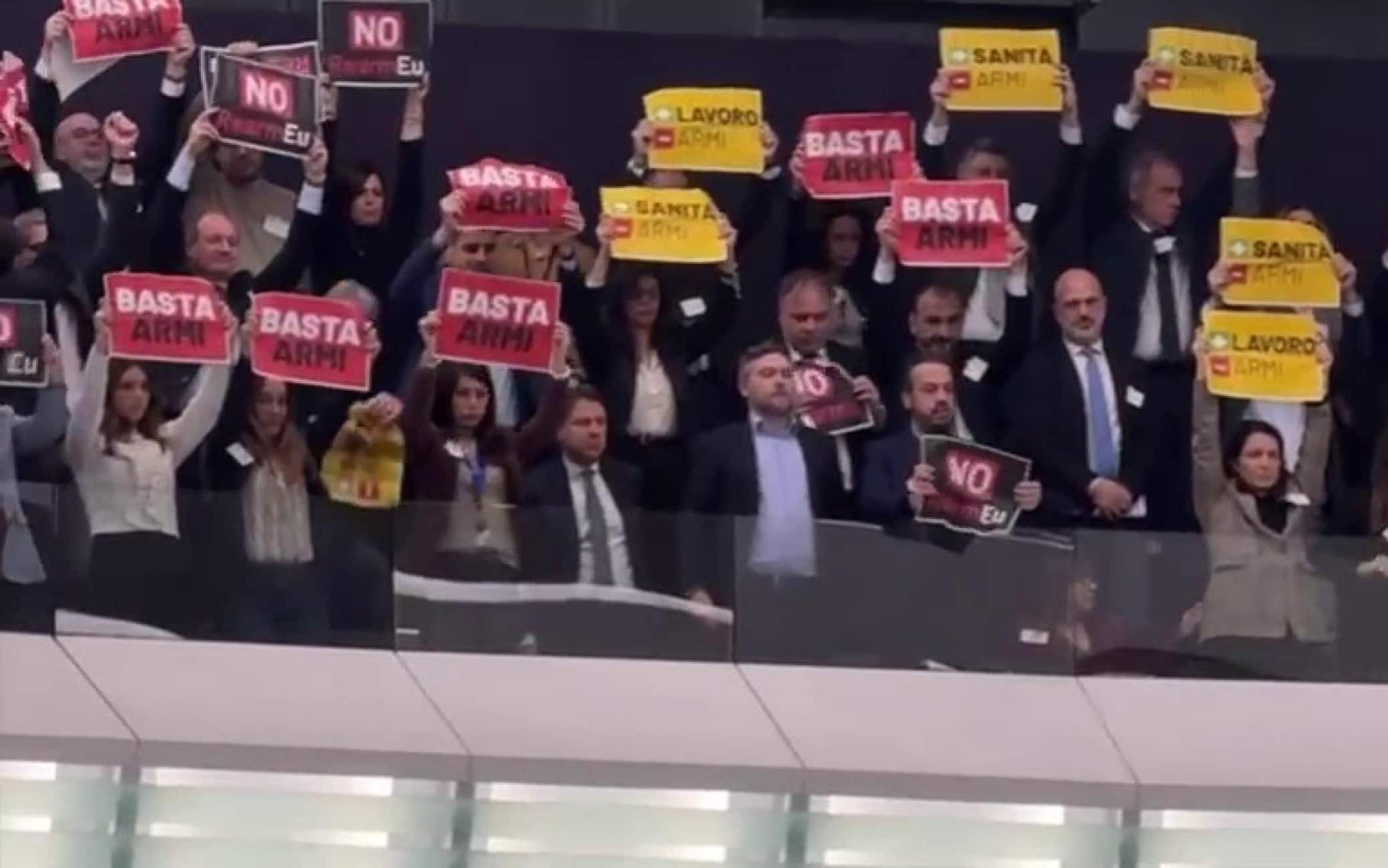 Protesta silenziosa contro il Rearm EU da parte dell'ex premier, Giuseppe Conte e della delegazione dei parlamentari anche nella tribuna destinata al pubblico del Parlamento europeo, 11 marzo 2025. Appena l'eurodeputato M5s Danilo Della Valle aveva finito di parlare, mentre stava ponendo una bandiera della pace al banco dei Commissari, la delegazione dei Cinque Stelle ha mostrato alcuni piccoli manifesti colorati con su scritto: "Basta armi", "No al riarmo" "Piu? lavoro meno armi".  ANSA/ UFFICIO STAMPA M5S ++++ ANSA PROVIDES ACCESS TO THIS HANDOUT PHOTO TO BE USED SOLELY TO ILLUSTRATE NEWS REPORTING OR COMMENTARY ON THE FACTS OR EVENTS DEPICTED IN THIS IMAGE; NO ARCHIVING; NO LICENSING +++