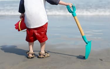 A small boy pauses to watch the surf while playing at Hampton Beach, New Hampshire, USA.