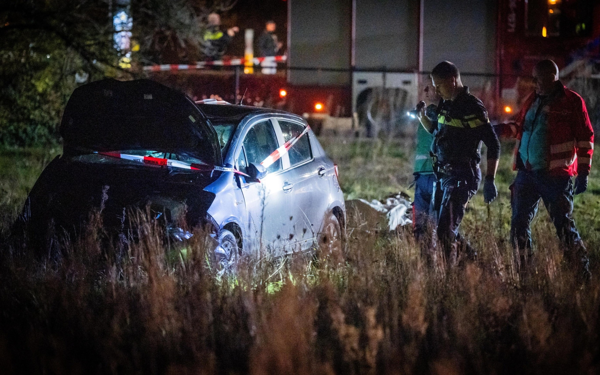epa12609171 A damaged car in a field at the scene of an accident on the Elburgerweg in Nunspeet, the Netherlands, 22 December 2025. According to police, a car drove into a group of people injuring at least nine people, including three with serious wounds.  EPA/ROLAND HEITINK