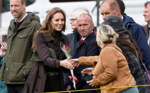 Britain's Prince William, Prince of Wales and Britain's Catherine, Princess of Wales, is handed a flower whilst watching training activities on the pitch while while visiting Bute Shinty Club in Rothesay, in the Isle of Bute, Scotland, on September 17, 2026. (Photo by Jeff J Mitchell / POOL / AFP)