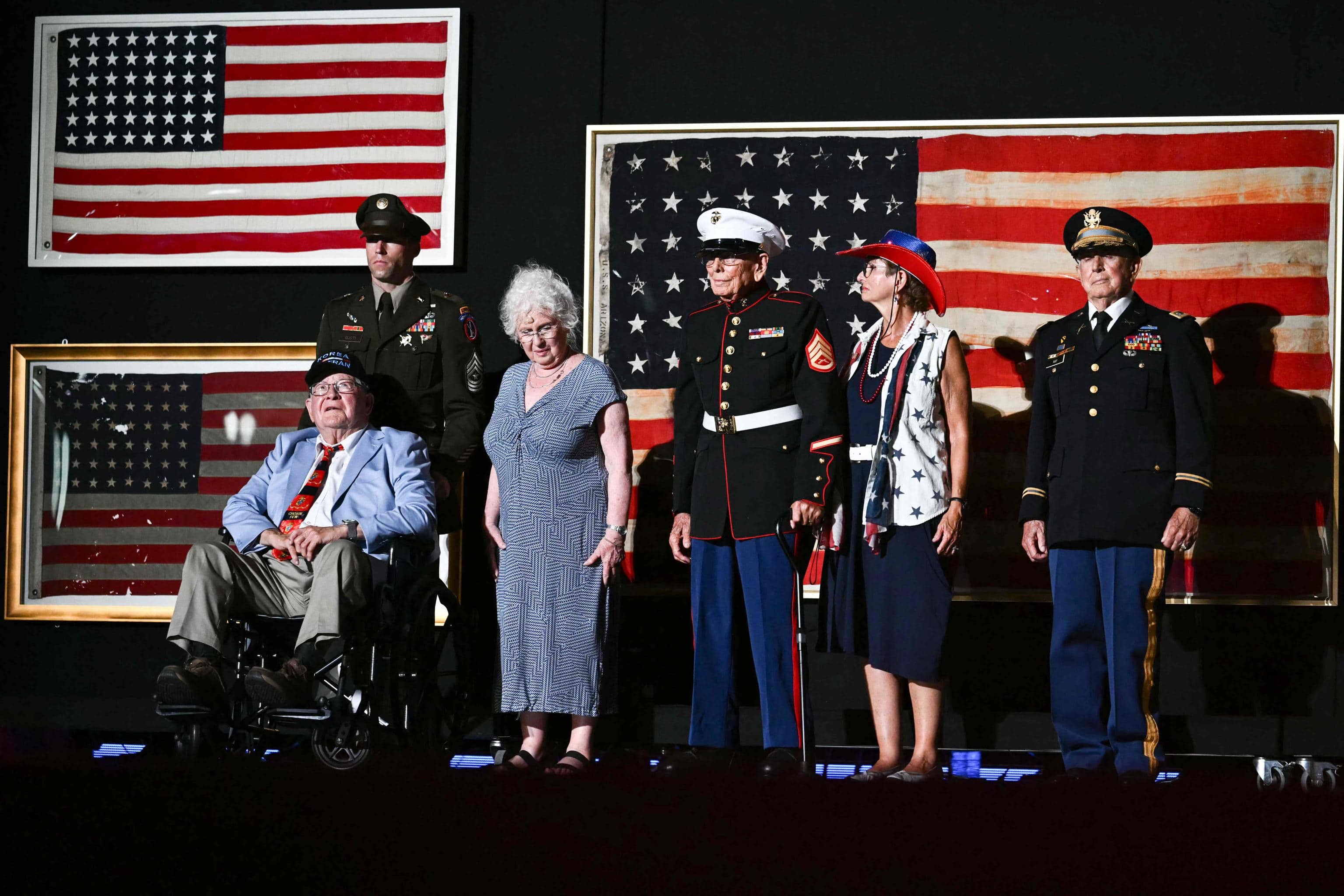 Retired US Marine Corps veteran Patrick Finn (L), retired Marine Private First Class Rudy Meekins (C) with their families appear on stage as US President Donald Trump (off frame) speaks during the "Salute to America" Independence Day celebration on the National Mall in Washington, DC, on July 4, 2026. The nation is marking the 250th anniversary of the United States Declaration of Indpendence. (Photo by Kent NISHIMURA / AFP)