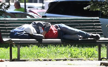 Un senza fissa dimora riposa su una panchina a Milano, 19 maggio 2021. ANSA/DANIEL DAL ZENNARO