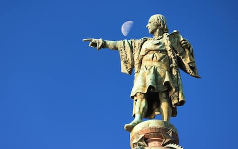 A statue dedicated to Christopher Columbus in the city centre of Barcelona, Spain with the moon in the background