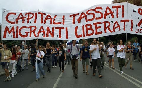 GEN14-20010719-GENOA, ITALY: Demonstrators carry a placard reading "Capitali tassati, Migranti liberati" (Put taxes on the capital, free the immigrants) as about 25 000 people protest in the center of Genua against the G8 (Group of Eight) summit, Thursday 19 July 2001, a day before the start of the conference. Heads of state and government of the G8 countries will meet here 20 to 22 July amid heightened security to deal with an expected 120,000 anti-globalisation demonstrators. EPA PHOTO EPA/ANJA NIEDRINGHAUS/hh