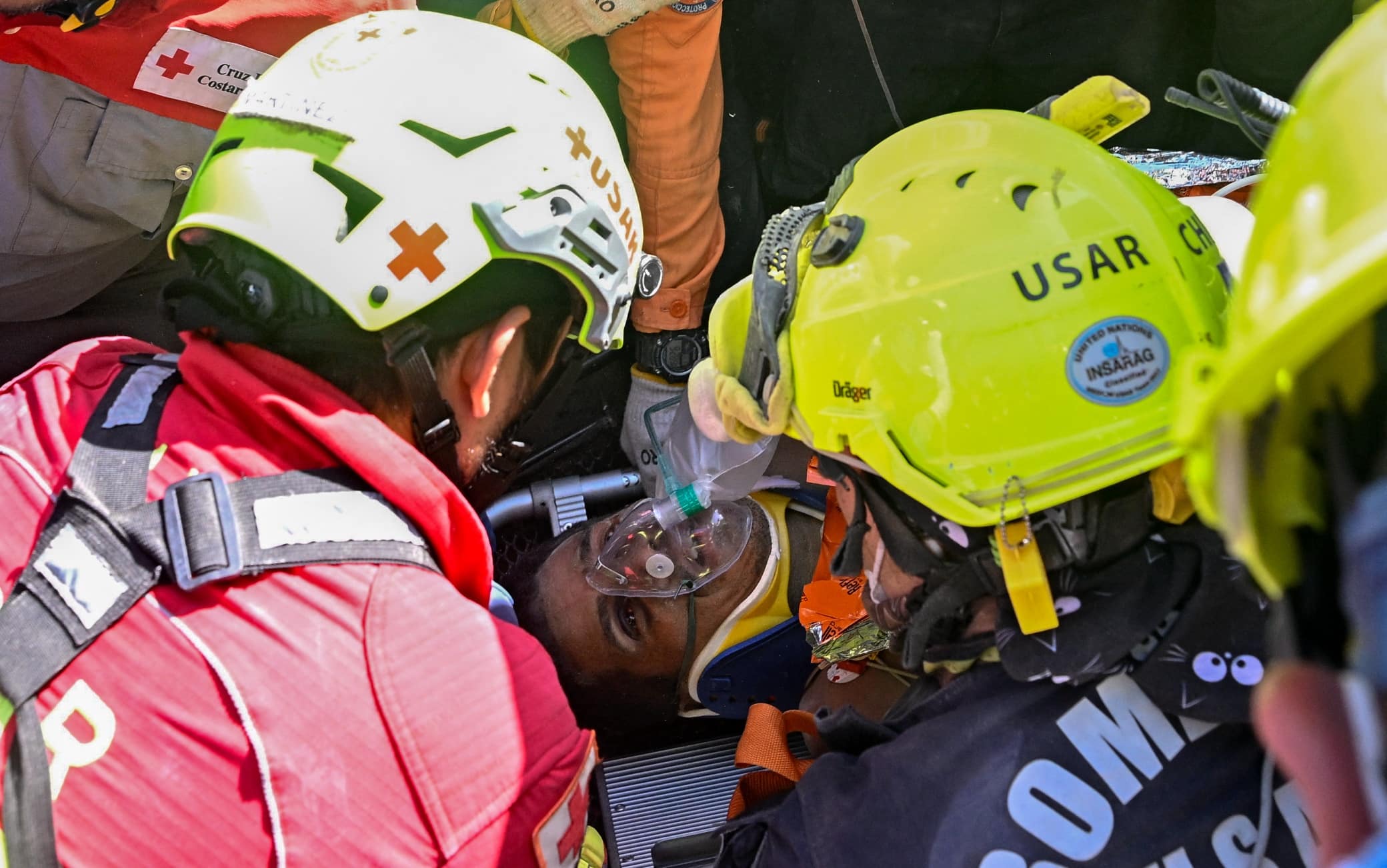 An international rescue team assists a survivor of Venezuela's twin earthquakes in Catia La Mar, La Guaira State, Venezuela on July 2, 2026, eight days after the quake. Hernan Gil, a 43-year-old security guard, had been buried in the booth of the seven-story building where he worked in Catia La Mar, a coastal area in the state of La Guaira devastated by the disaster. (Photo by Federico PARRA / AFP)
