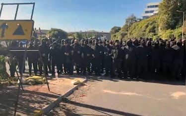 Un frame mostra decine di persone vestite di nero e con il passamontagna hanno bloccato la strada al porto di Dover, nel Kent. +++ NPK +++ +++ FACEBOOK/ALESSANDRO DI BATTISTA +++ ATTENZIONE L'IMMAGINE NON PUO' ESSERE RIPRODOTTA SENZA L'AUTORIZZAZIONE DELLA FONTE CUI SI RINVIA +++ NPK +++
