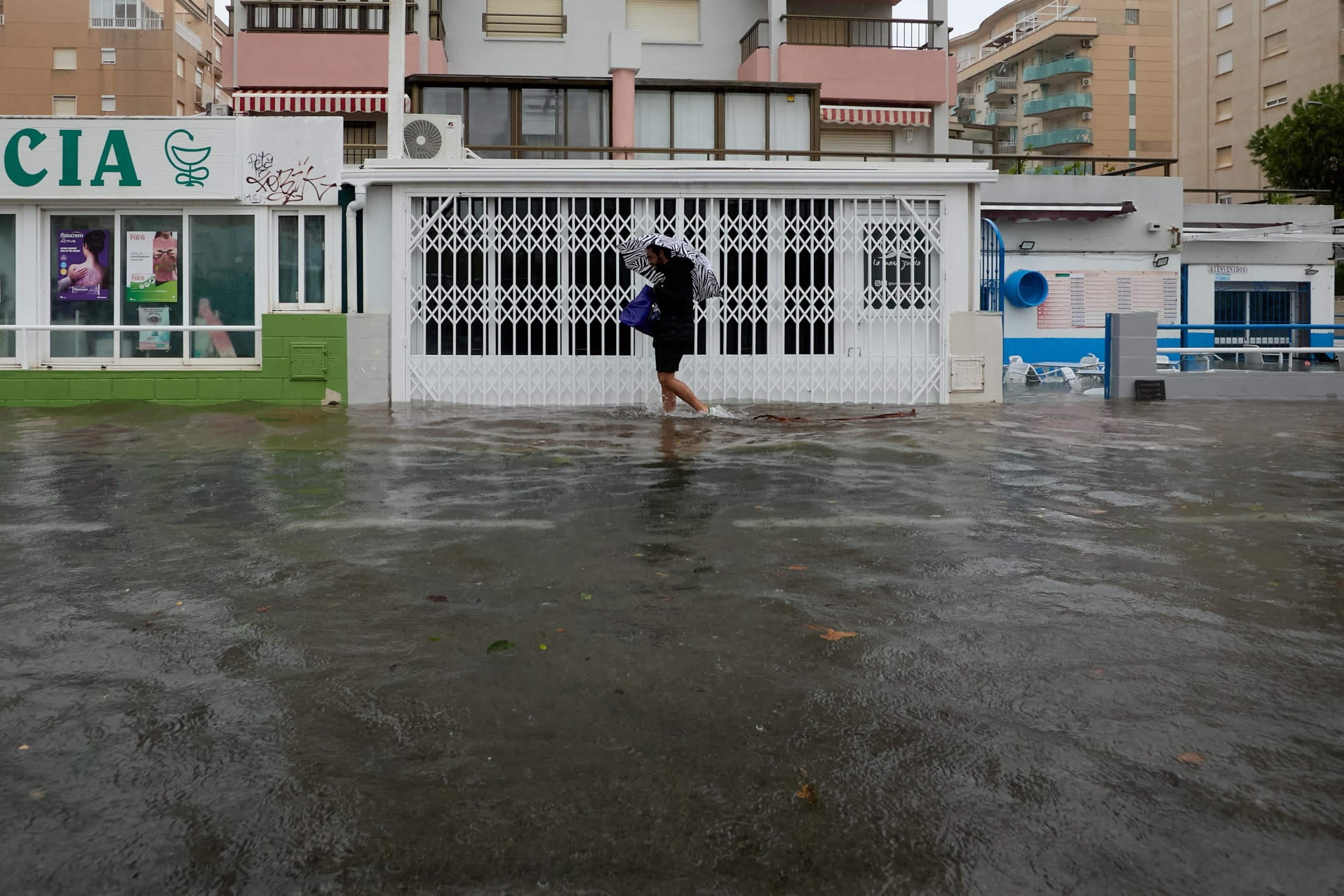 epa13314998 A man walks down a flooded street after heavy rainfall in Gandia, Valencia, Spain, 19 October 2026.  Spain's State Meteorological Agency (Aemet) forecasts that the unsettled conditions caused by Storm Adam will persist across mainland Spain and the Balearic Islands, with very severe to torrential storms expected in the Valencian Community, along the southeastern coast and in the Balearic Islands.  EPA/Natxo Frances