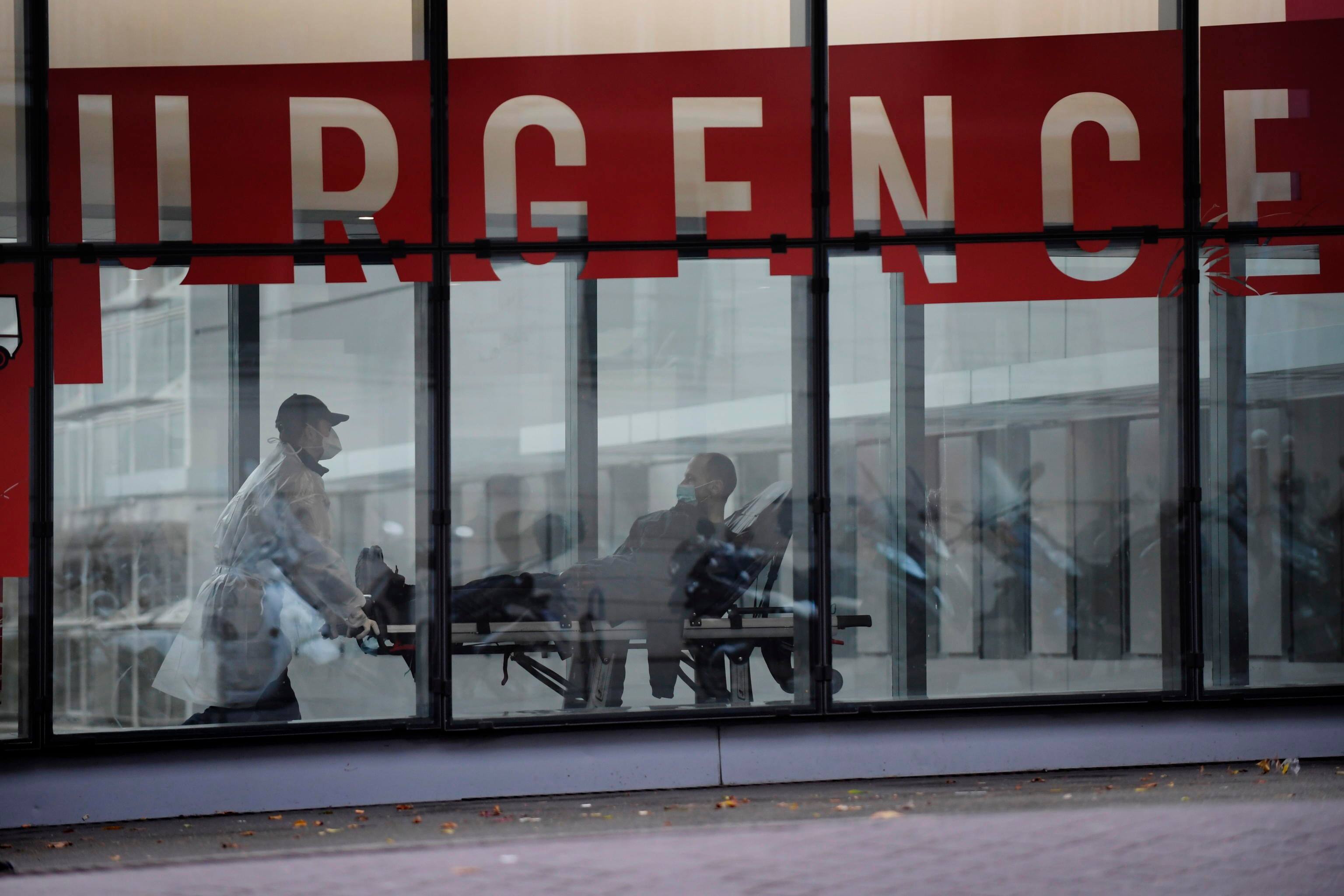 epa08780297 Medical staff wearing protective facial masks transport a patient on a gurney inside the Tenon Hospital in Paris, France, 28 October 2020. French President Emmanuel Macron will unveil new measures to stem the Covid-19 epidemic in a television speech on 28 October 2020.  EPA/JULIEN DE ROSA