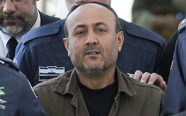 epa03077319 Handcuffed Palestinian Fatah leader Marwan Barghouti is escorted by Israeli police to the Magistrate Court in Jerusalem, 25 January 2012, after testifying in a US civil lawsuit against the Palestinian leadership. Barghouti, sentenced to life imprisonment in 2002 for being involved in anti-Israeli attacks when he led the Tanzim, a Fatah's militant faction, during the Second Intifada in 2000, was cited as saying that the Middle East conflict would only end only when Israel withdraws to the pre-1967 borderlines and a Palestinian state was established. Barghouti refused to testify in court today.  EPA/ABIR SULTAN