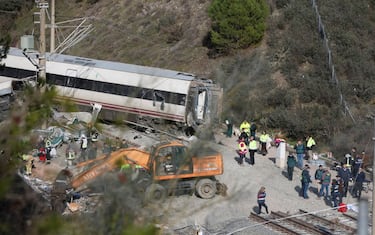 epa12664515 Spanish Civil Guard agents search for evidence beneath a damaged wagon from one of the trains involved in the 18 January crash between two high-speed train sets in Adamuz, Spain, 20 January 2026. At least 41 people were killed after a high-speed train carrying more than 300 passengers derailed and collided with an oncoming train on an adjacent track, and emergency services remain at the scene as recovery efforts continue.  EPA/Jorge Zapata