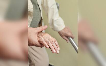 Elderly woman holding on handrail with caregiver