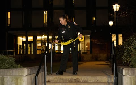 A Brown University police officer cordons off access to the Barus & Holley engineering building at Brown University campus in Providence, Rhode Island, on December 13, 2025. A gunman killed two people and critically wounded eight others in the afternoon of December 13 at prestigious Brown University, authorities said, urging people in the area to remain in lockdown as the attacker was still at large. (Photo by Bing Guan / AFP)
