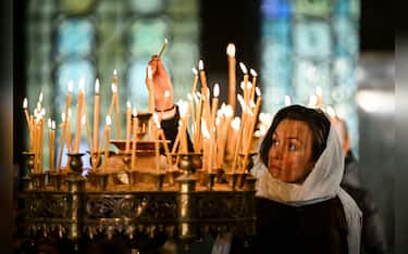 An Orthodox Christian believer lights a candle during a Christmas mass at the golden-domed Alexander Nevski Cathedral, in Sofia, on December 25, 2024. Bulgaria, unlike some other fellow Orthodox countries, celebrates Christmas on December 25th. (Photo by Nikolay DOYCHINOV / AFP) (Photo by NIKOLAY DOYCHINOV/AFP via Getty Images)